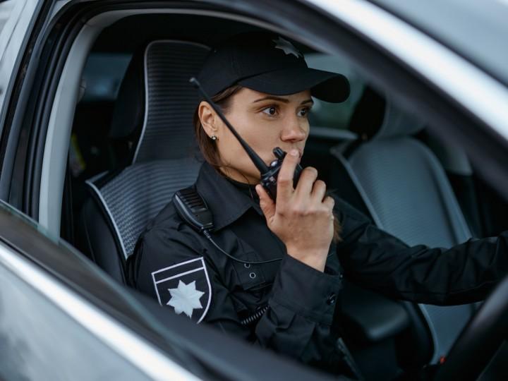 A cop speaks on walkie talkie while in vehicle